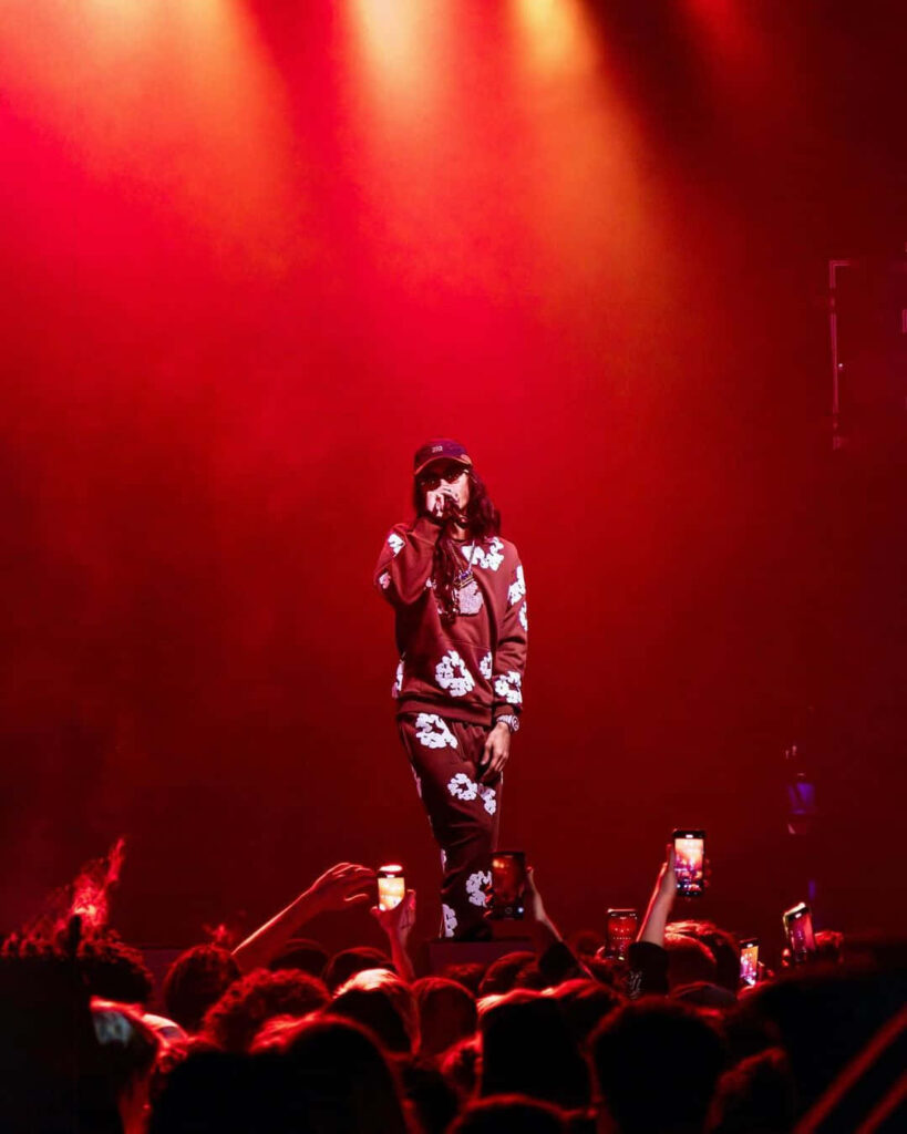 BabyTron performing live on stage with vibrant red and orange lights captivating fans Wallpaper