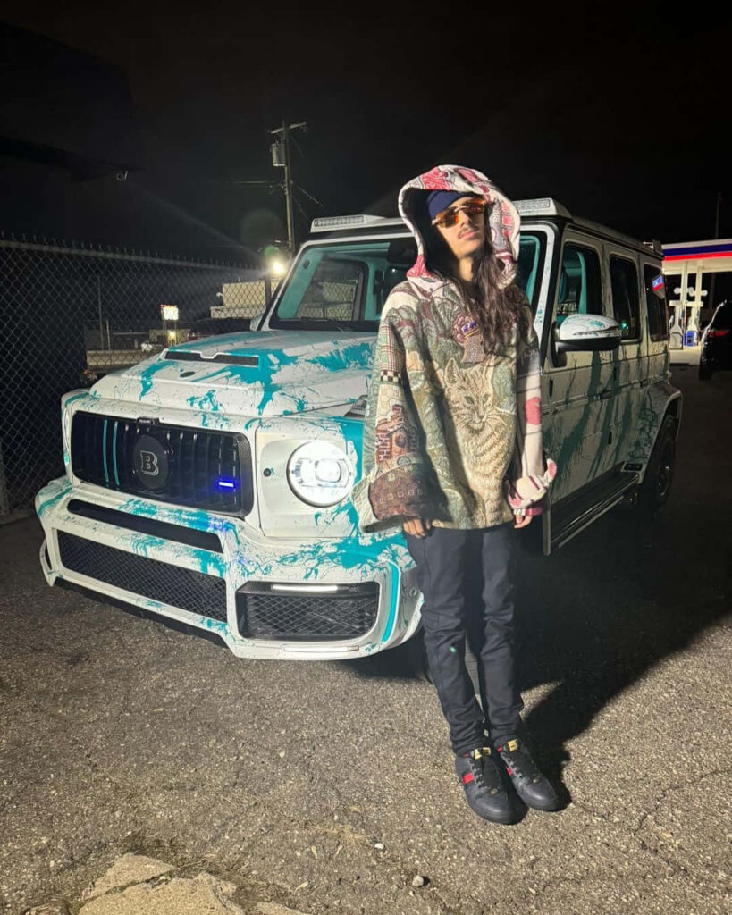 BabyTron rapper poses confidently by custom-painted Mercedes G-Wagon with wallpaper background