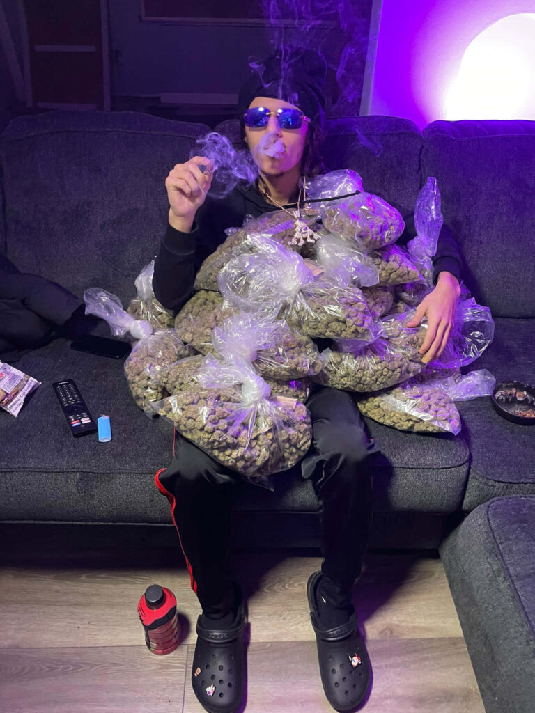 BabyTron rapper on couch with cannabis bags wearing sunglasses headscarf purple lighting background Wallpaper