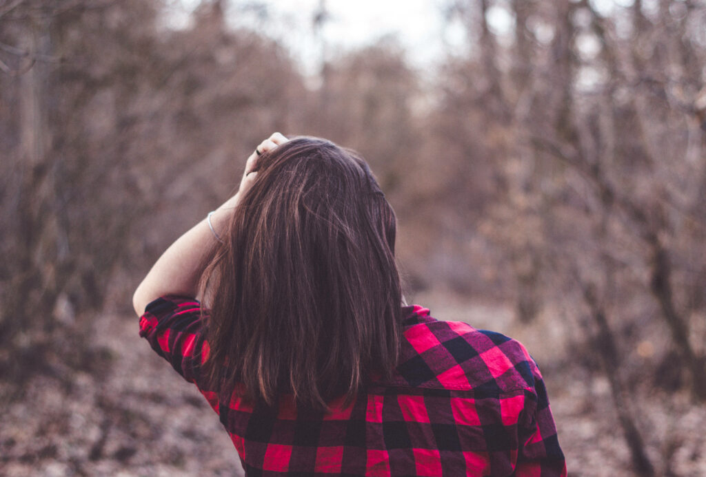 Boldly Clad Woman Poses in Serene Checkered Forest Landscape Wallpaper