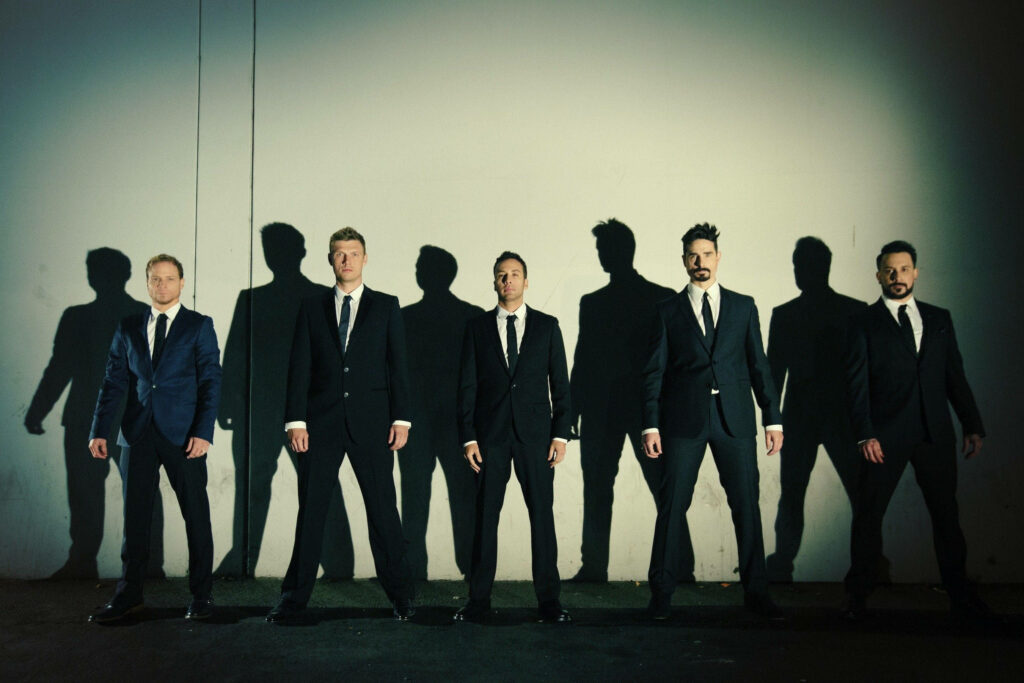 Backstreet Boys in suits with dramatic shadows against soft lit wall classic group portrait wallpaper