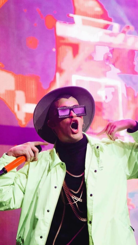Bad Bunny performing in neon green polo and signature hat vibrant colorful concert backdrop wallpaper