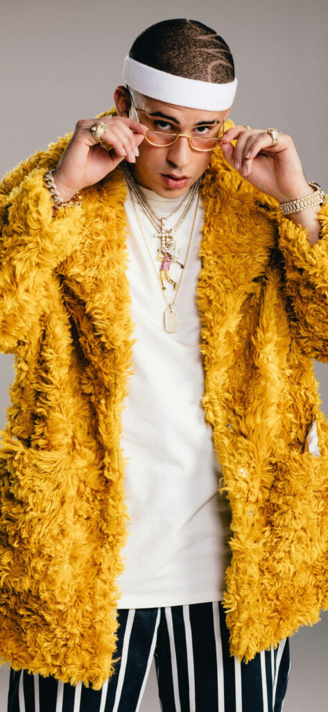 Bad Bunny in vibrant yellow fur jacket stylish accessories sunglasses bold Puerto Rican rapper fashion Wallpaper