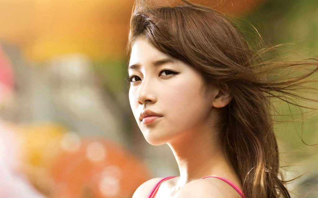 Young Bae Suzy from Miss A in natural sunlight with flowing hair and serene outdoor background wallpaper