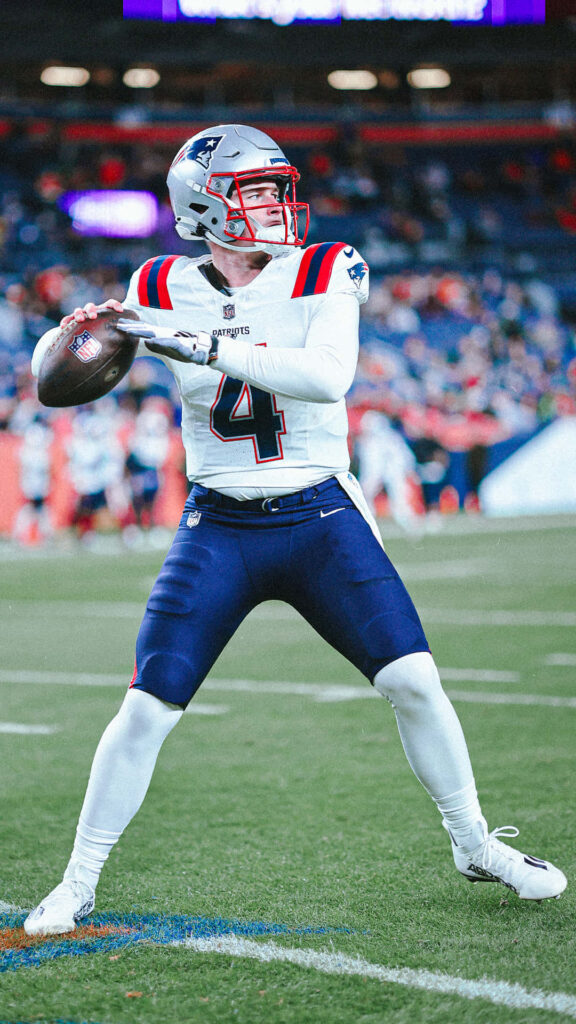 Bailey Zappe throwing a pass in New England Patriots uniform during an NFL game action shot Wallpaper