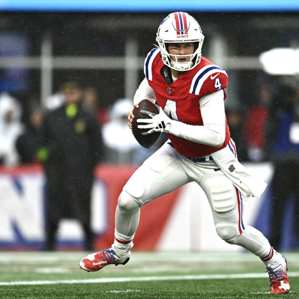 Bailey Zappe in New England Patriots uniform poised to throw a pass on football field wallpaper
