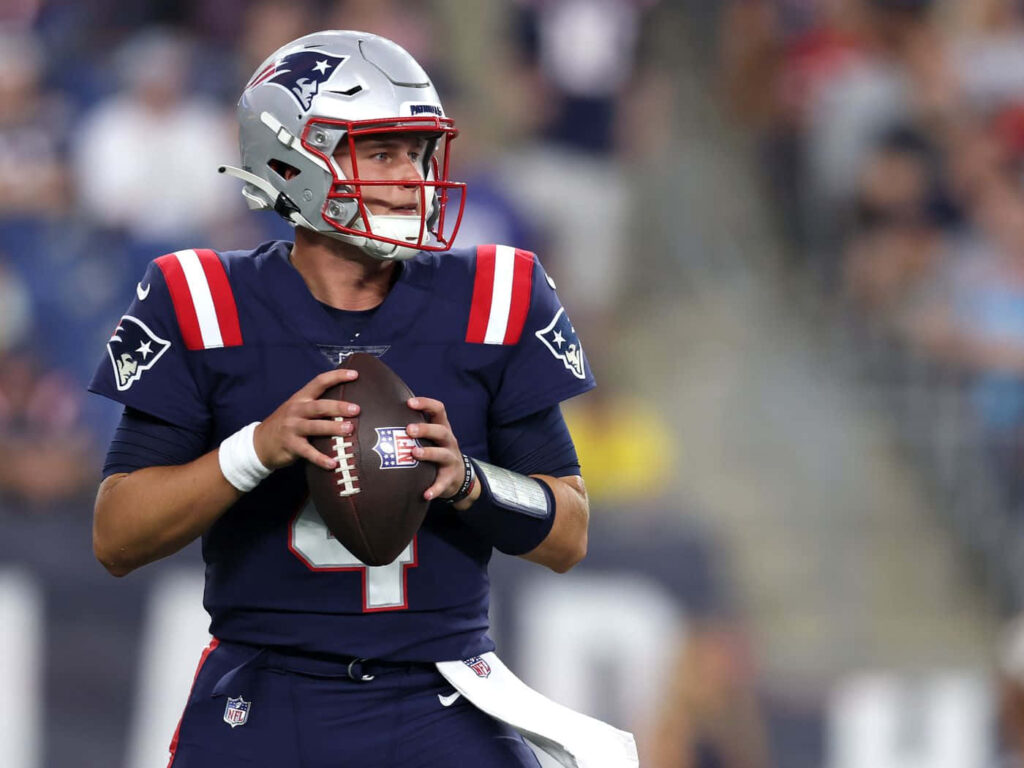 Bailey Zappe in New England Patriots uniform focused throwing football during game action wallpaper