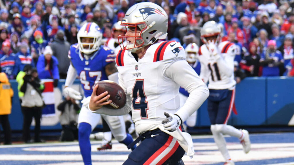Bailey Zappe New England Patriots running with football during game action on field wallpaper background