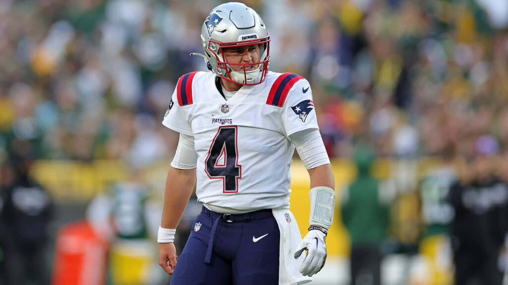 Bailey Zappe in New England Patriots uniform poised on football field ready for next play wallpaper