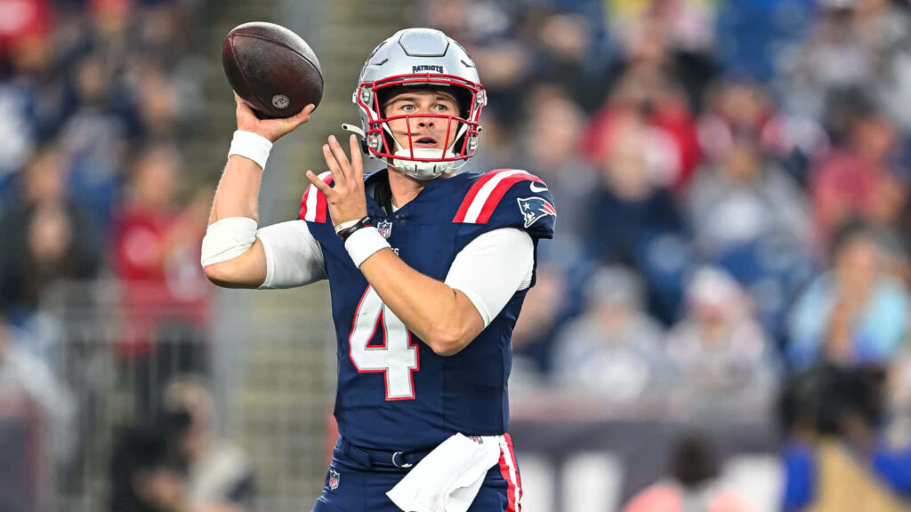 Bailey Zappe in New England Patriots uniform focused throwing football during game wallpaper