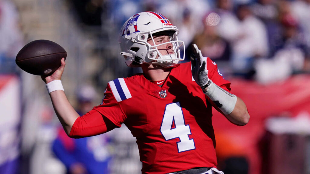 Bailey Zappe in red football uniform throwing a pass during intense game action wallpaper
