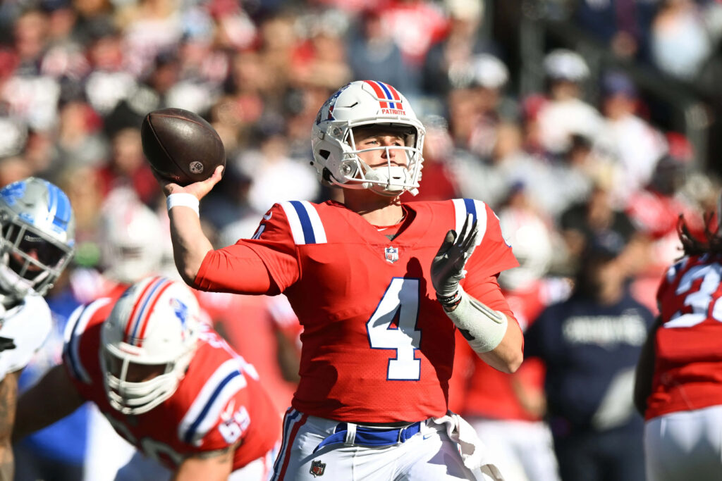 Bailey Zappe in red Patriots uniform number 4 prepares to throw a pass in football game action Wallpaper