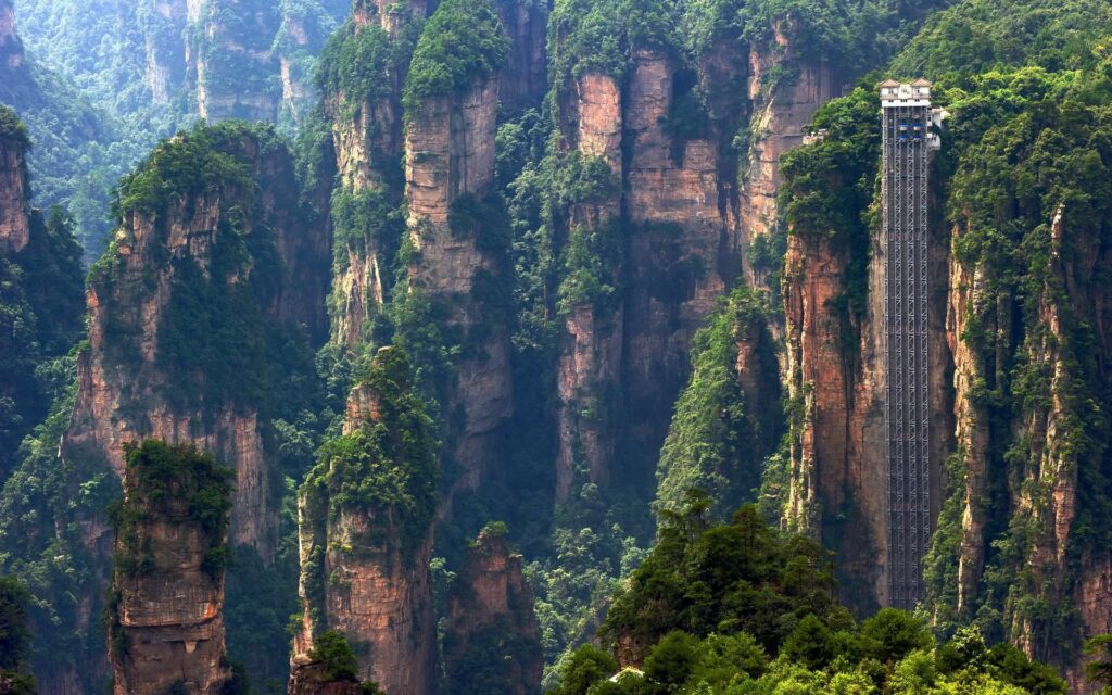 Bailong Elevator ascending sandstone pillars Zhangjiajie National Forest Park lush green cliffs Wallpaper