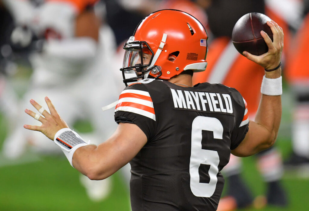 Baker Mayfield in black uniform throwing football during intense game action wallpaper background