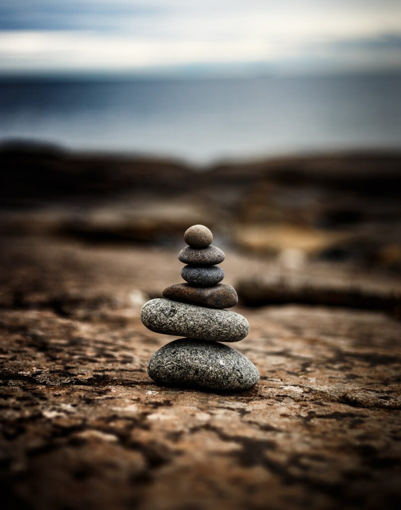 Stack of smooth stones balanced in nature background representing harmony and tranquility wallpaper