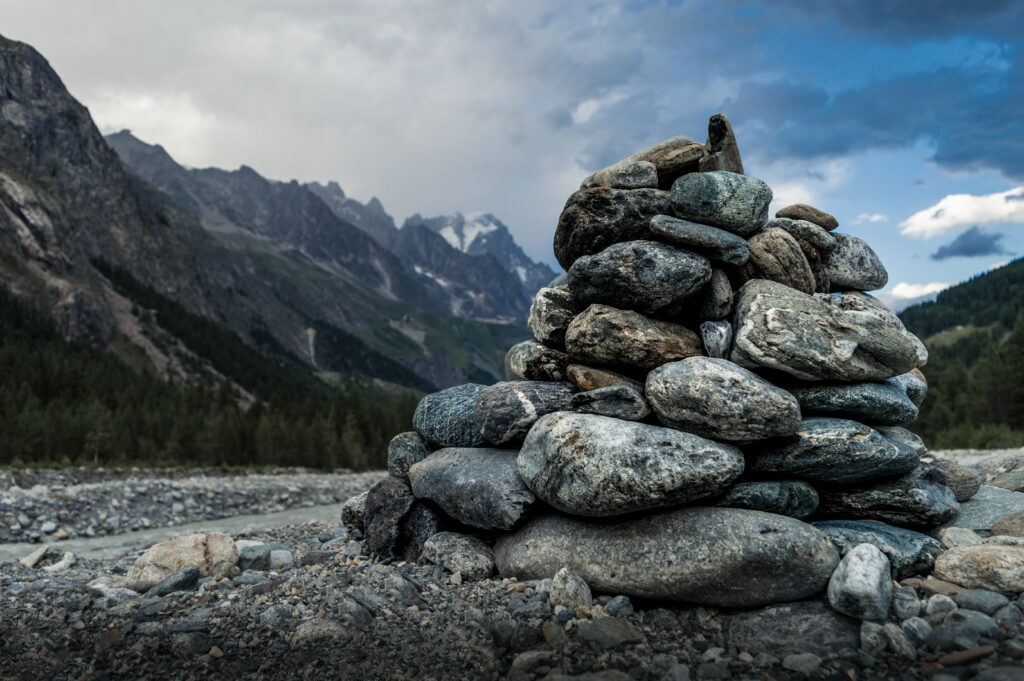 Balanced smooth stone stack foreground with dramatic mountain and moody cloudy sky wallpaper
