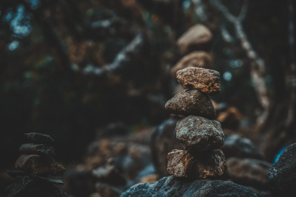 Stacked weathered stones balanced on each other with blurred natural background wallpaper