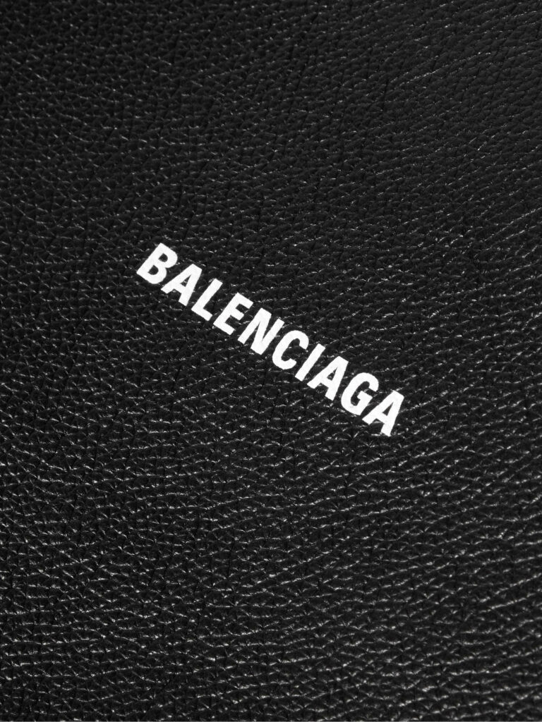 Balenciaga logo in bold white letters on textured black leather luxury wallpaper background