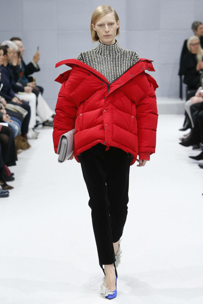 Model walks runway in bold red Balenciaga puffer jacket with patterned top and black pants Wallpaper