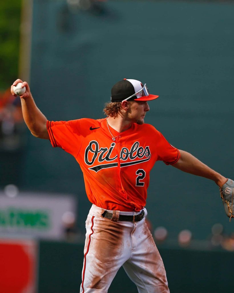 Baltimore Orioles Gunnar Henderson mid-throw in orange jersey dynamic baseball wallpaper background