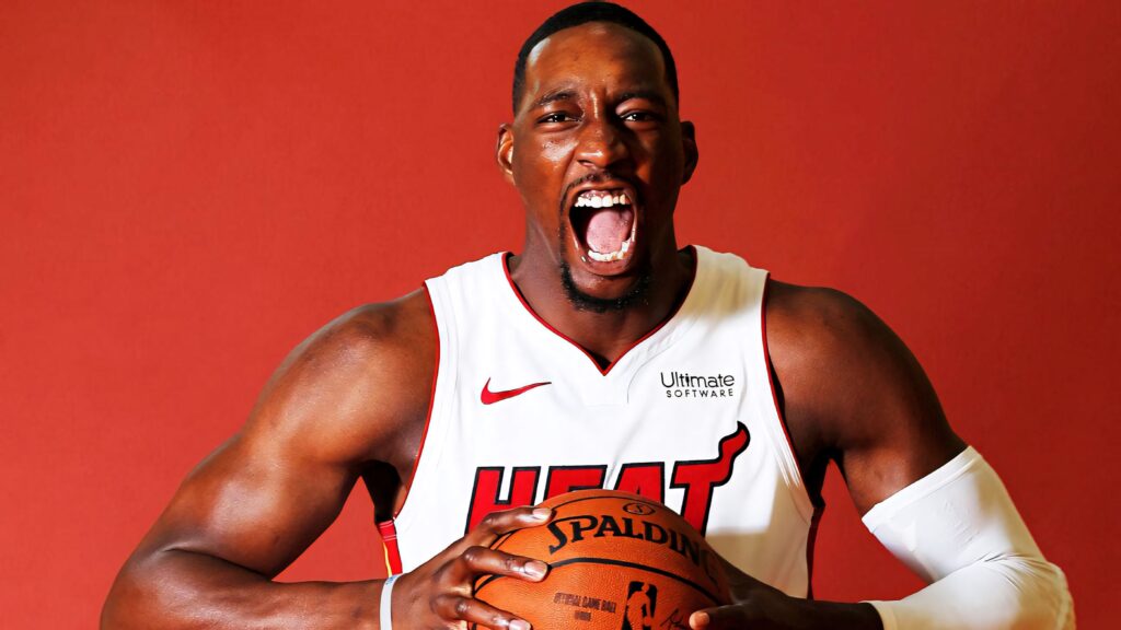 Dynamic portrait of Miami Heat star Bam Adebayo holding basketball on vibrant red background wallpaper