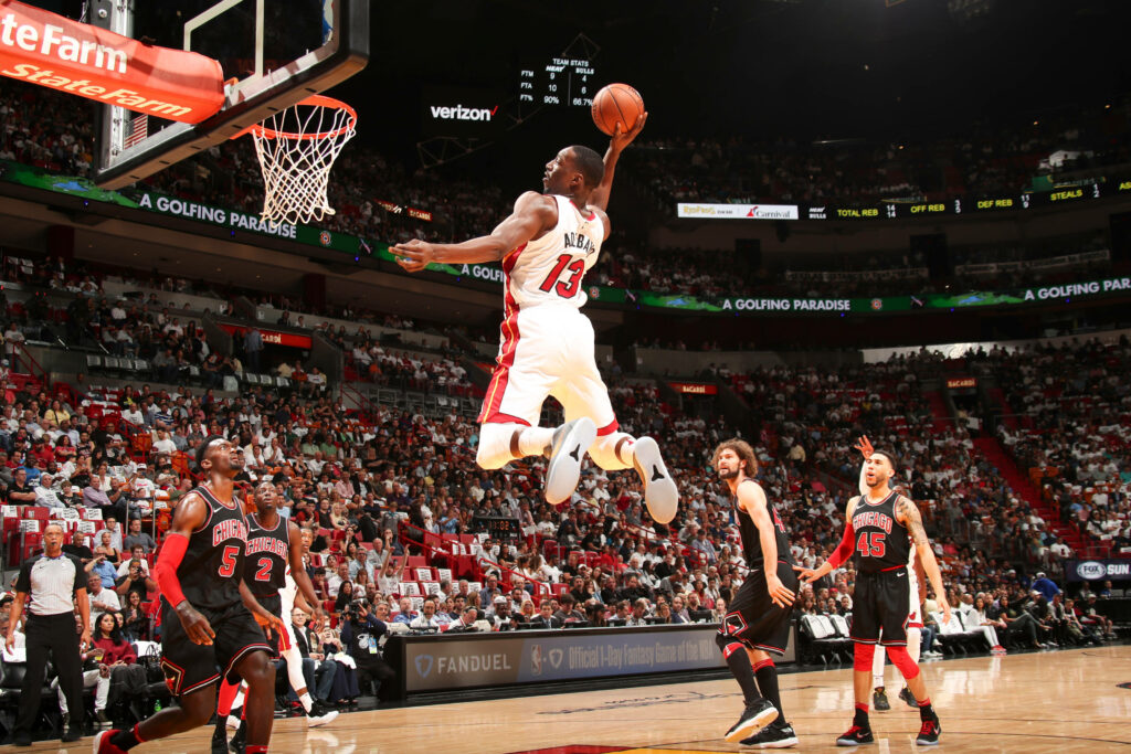 Bam Adebayo mid-air slam dunk NBA game intense action vibrant basketball court wallpaper