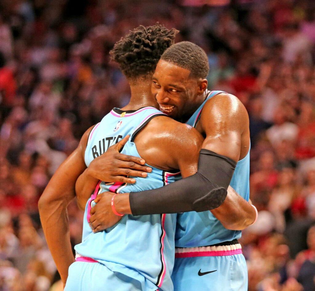 Bam Adebayo and Jimmy Butler celebrating on court in Miami Heat uniforms showing teamwork Wallpaper