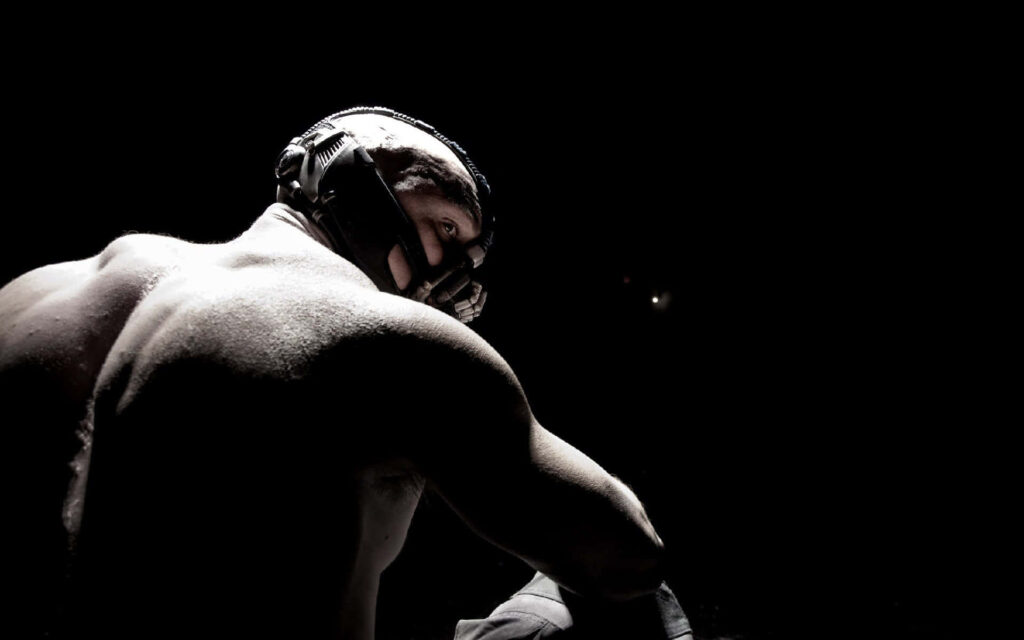 Bane from DC Comics intense gaze muscular build dramatic shadowed portrait wallpaper background