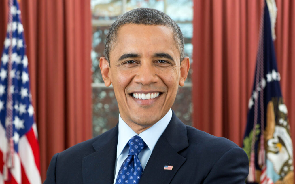 Barack Obama standing confidently in the Oval Office with a warm smile wallpaper background