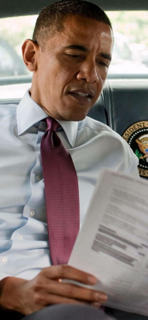 Barack Obama focused reading document seated leadership moment wallpaper background