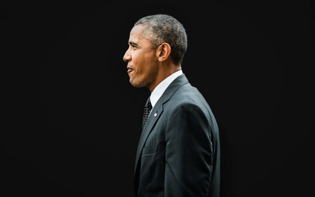 Side view of Barack Obama in formal suit against black background presidential wallpaper