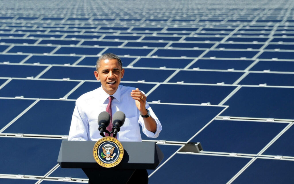 Barack Obama in white long sleeves speaking at solar panel field promoting clean energy innovation Wallpaper