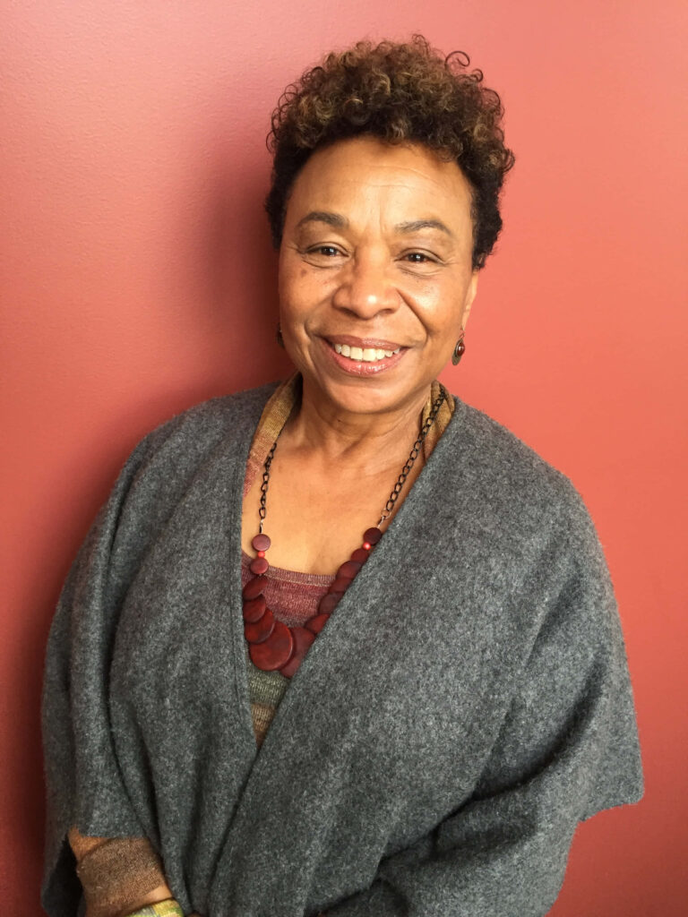 Barbara Lee smiling warmly against solid pink background vibrant phone wallpaper design