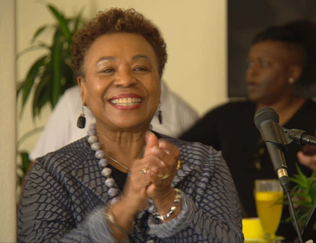 Barbara Lee clapping and smiling warmly in an uplifting positive wallpaper background