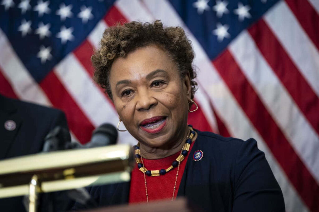 Barbara Lee delivering a confident speech with American flags backdrop wallpaper background