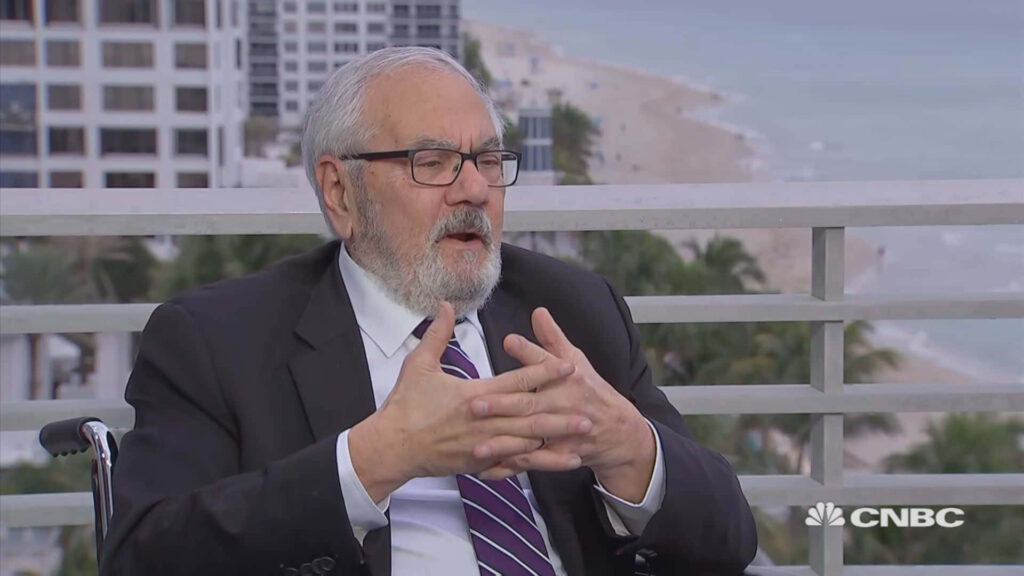 Barney Frank speaking in CNBC interview with beachside cityscape background wallpaper
