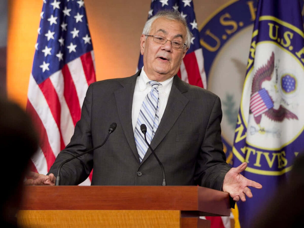 Barney Frank delivering passionate speech at podium with American flags and House seal backdrop Wallpaper