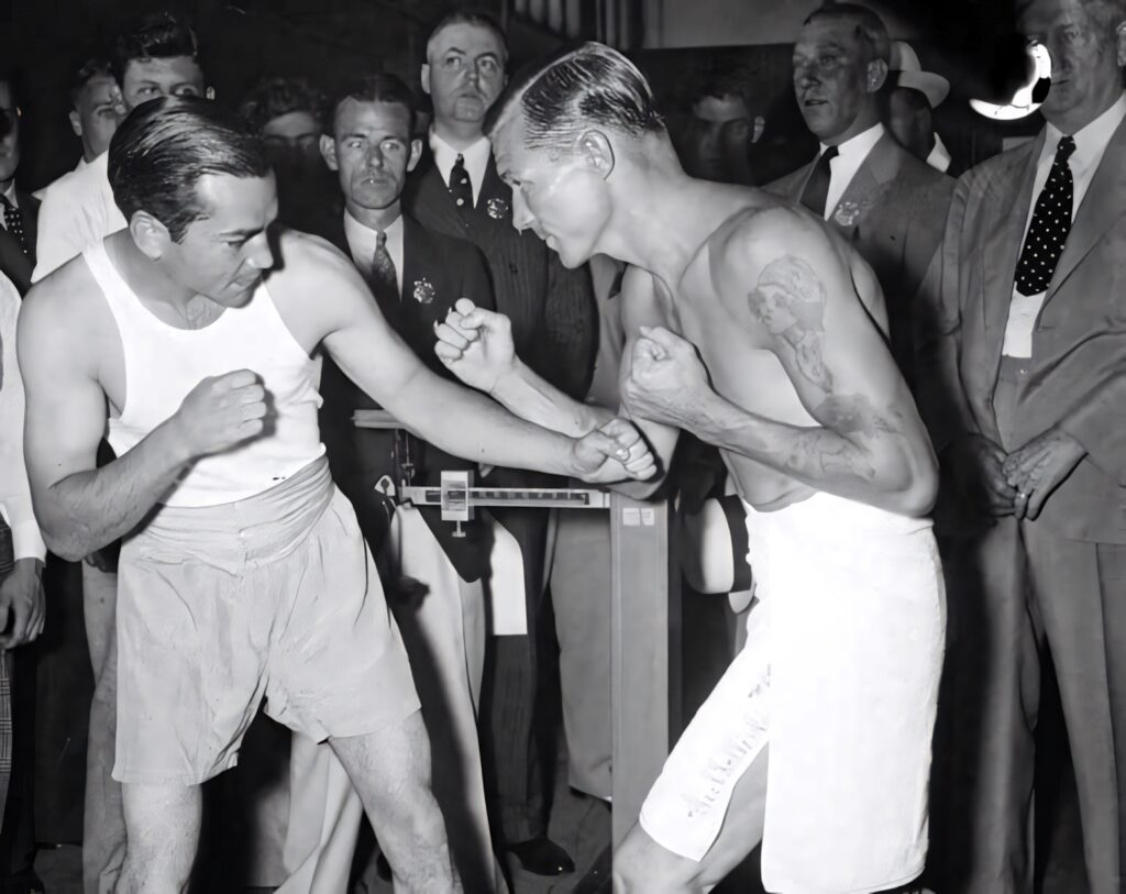 Barney Ross in boxing stance facing opponent with crowd watching historic black and white scene Wallpaper