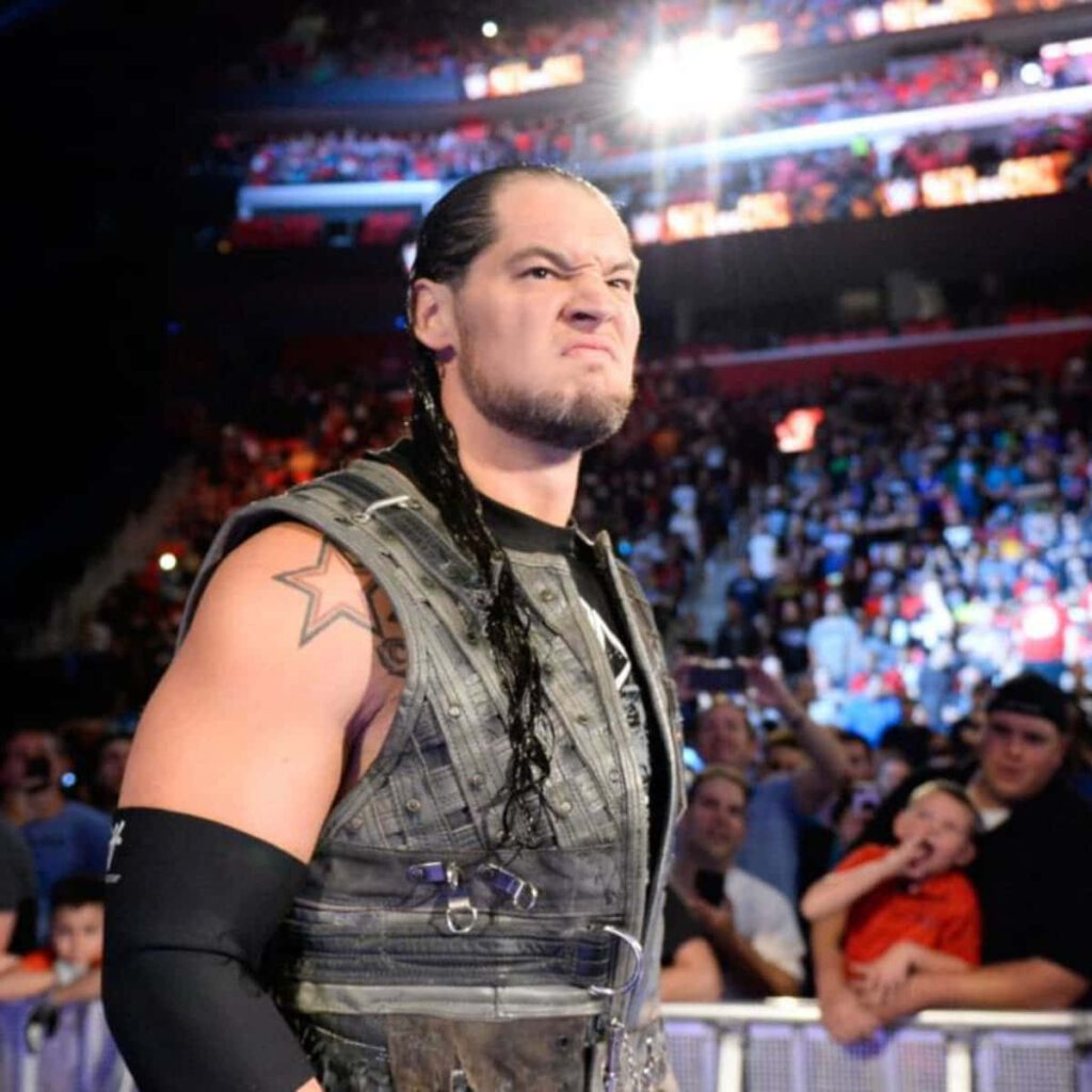Close-up of wrestler Baron Corbin in signature attire with intense expression in packed arena Wallpaper