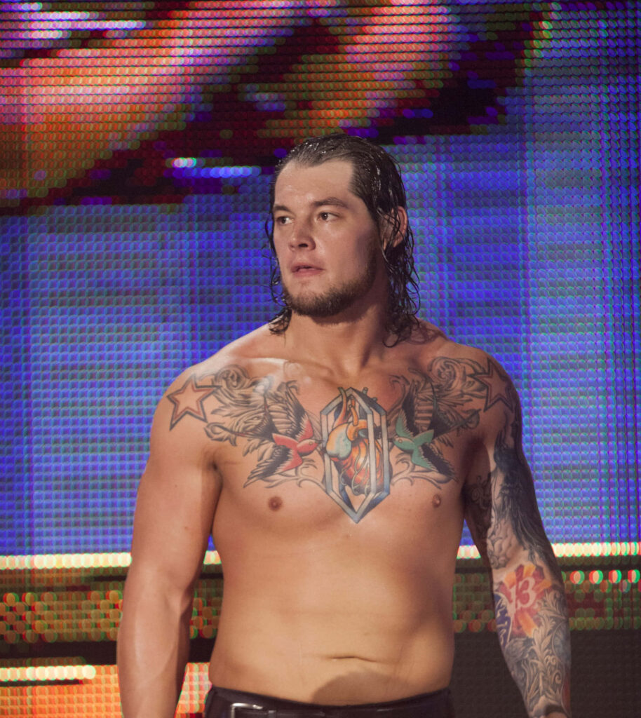 Wrestler Baron Corbin topless in ring showing tattooed chest and arm colorful stage background Wallpaper
