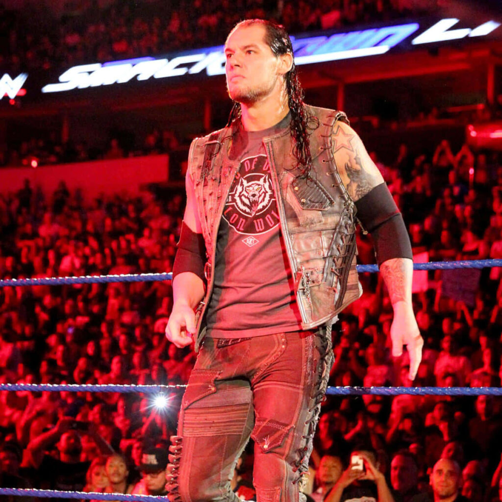 WWE Superstar Baron Corbin stands focused in the ring under arena lights with cheering crowd Wallpaper