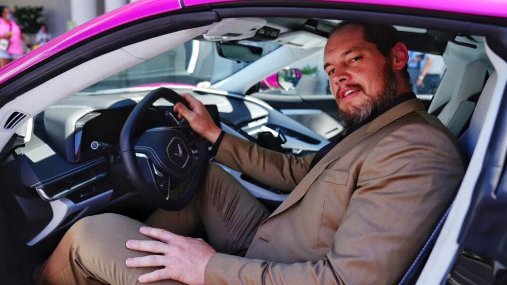 Wrestler Baron Corbin in tan suit driving sleek sports car wallpaper background style