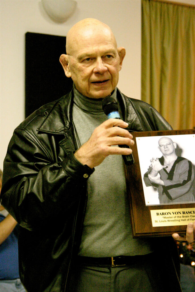 Baron Von Raschke retired wrestler holding memorabilia portrait speaking microphone celebration Wallpaper