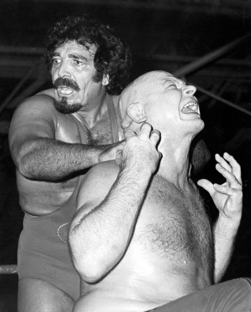 Wrestler Baron Von Raschke struggles in powerful hold by Sheik Adnan El Kaissey intense match wallpaper