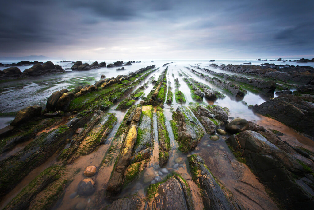 Dramatic Barrika coastline Spain rugged mossy rocks misty horizon moody cloudy sky wallpaper background