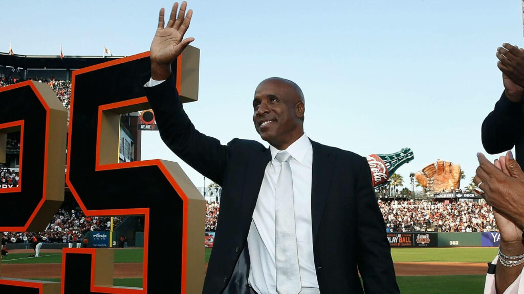 Barry Bonds in suit at ballpark celebration next to giant number 25 with wallpaper background