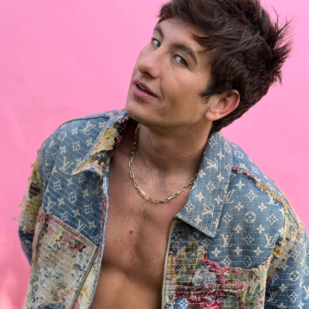 Barry Keoghan posing confidently in patterned denim jacket and gold chain on pink background Wallpaper