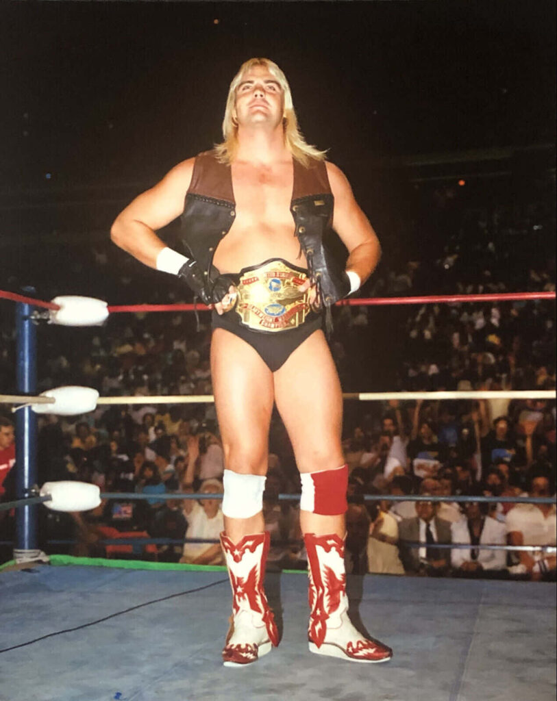 Barry Windham in wrestling ring with championship belt black trunks sleeveless vest cowboy boots Wallpaper