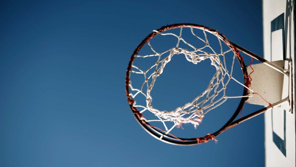 Low-angle view of basketball hoop and white net against clear blue sky outdoor sports background Wallpaper