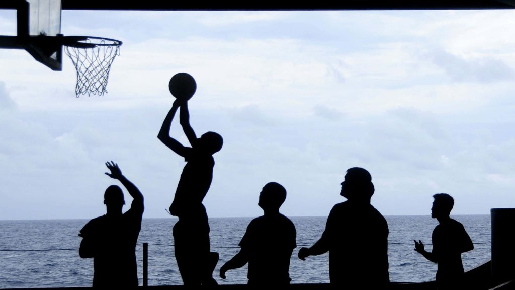 Basketball player mid-shot silhouette on ship deck with ocean and cloudy horizon background wallpaper
